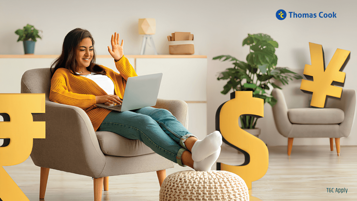Woman waving at a laptop on a chair, surrounded by 3D rupee, dollar, and yen symbols, doing Thomas Cook forex video KYC.