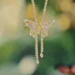 A platinum and gold diamond-encrusted butterfly pendant from the Hidden Garden collection hangs against a soft green backg...