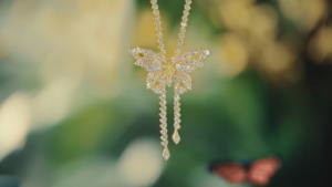A platinum and gold diamond-encrusted butterfly pendant from the Hidden Garden collection hangs against a soft green backg...