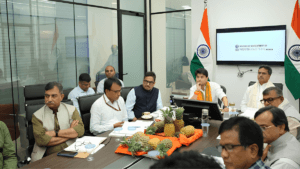 Officials at a conference table with pineapples on display and Indian flags during the Tripura mission launch.