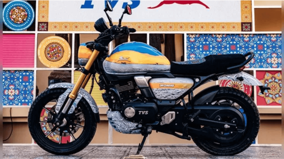 Custom TVS Ronin ROK Edition motorcycle with a blue, orange, and white fuel tank parked against a Kutchi art backdrop.