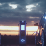 Two electric vehicles charging at an illuminated station at sunset, highlighting Indian passenger car localisation.