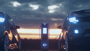 Two electric vehicles charging at an illuminated station at sunset, highlighting Indian passenger car localisation.