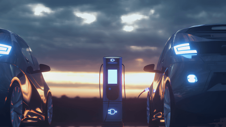 Two electric vehicles charging at an illuminated station at sunset, highlighting Indian passenger car localisation.