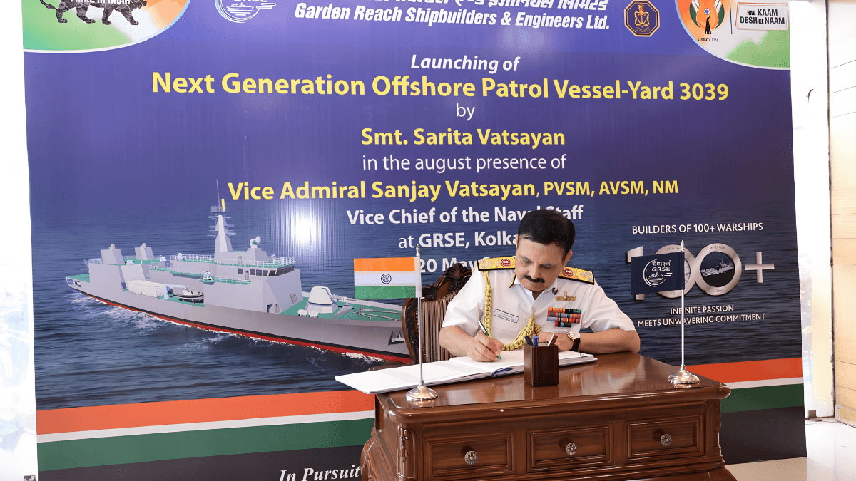Vice Admiral Sanjay Vatsayan in white naval uniform signing an official registry book at a wooden desk in Kolkata.