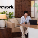 Two people using a laptop in a modern lounge with a bird mural at the WeWork Worldmark 6 office in Aerocity.