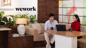 Two people using a laptop in a modern lounge with a bird mural at the WeWork Worldmark 6 office in Aerocity.