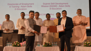 Officials hold open document folders on a stage with a Gujarat Skill Development backdrop for Kutch ITIs.