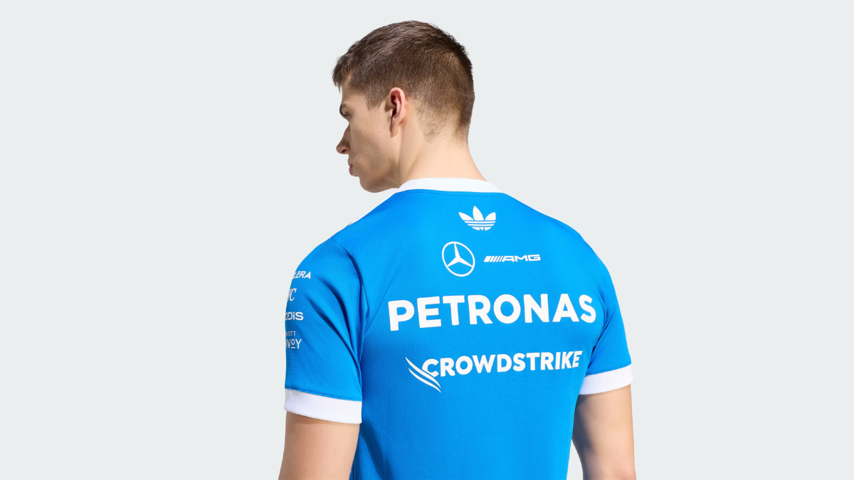Retro F1 racing gear arrives in India starting at ₹2,999 2 Back view of a man in a blue t-shirt with white Mercedes and adidas Trefoil logos, highlighting the apparel design.