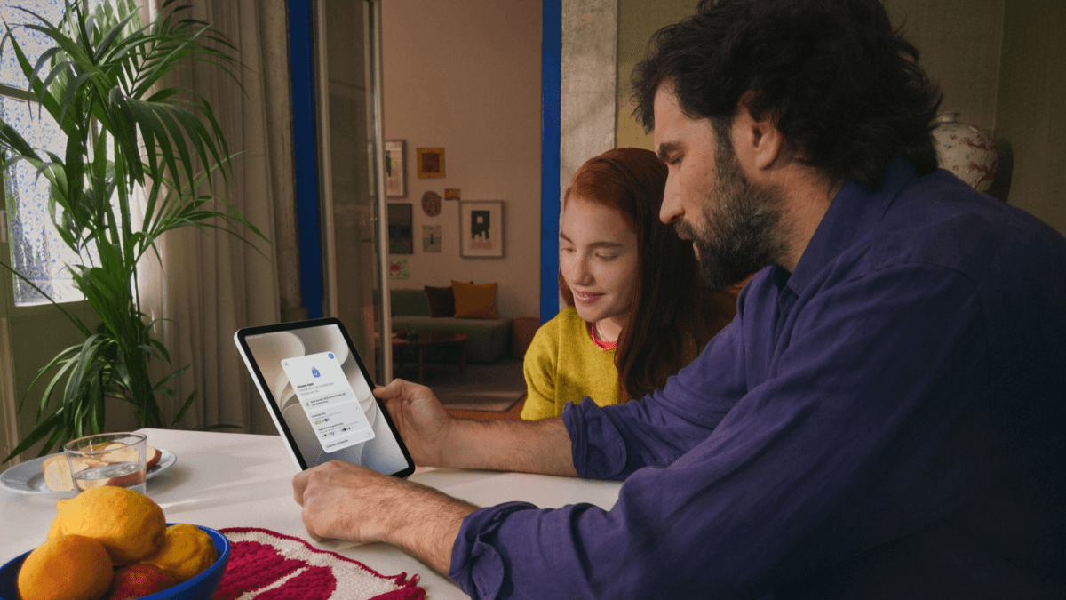 Blocking violent content is now standard for users under 18 2 A father and daughter looking at an iPad screen displaying the new child account privacy setup menu at home in India.