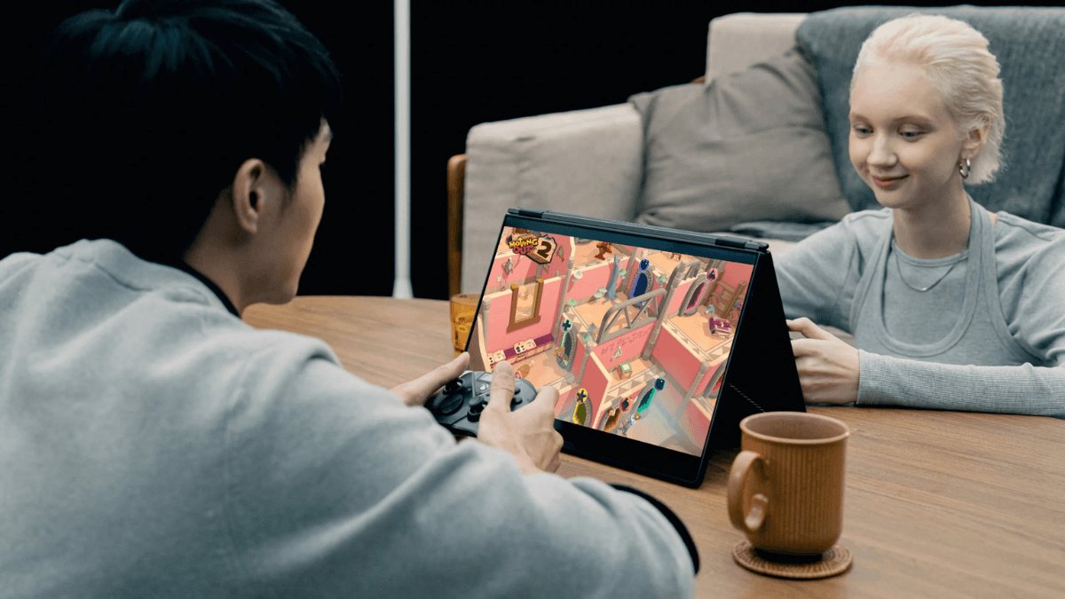 The ultra-thin laptop that makes desktop rigs feel obsolete 2 A man and woman at a table looking at an ASUS laptop screen playing a video game, with a brown mug.