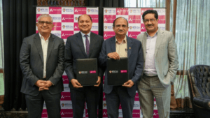 Four men in suits holding folders before a branded backdrop at the BITS Pilani Hyderabad campus partnership launch.