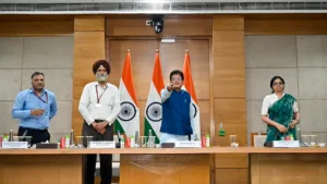 Piyush Goyal pressing a remote at a desk alongside three officials and Indian flags, inaugurating the BHAVYA portal.