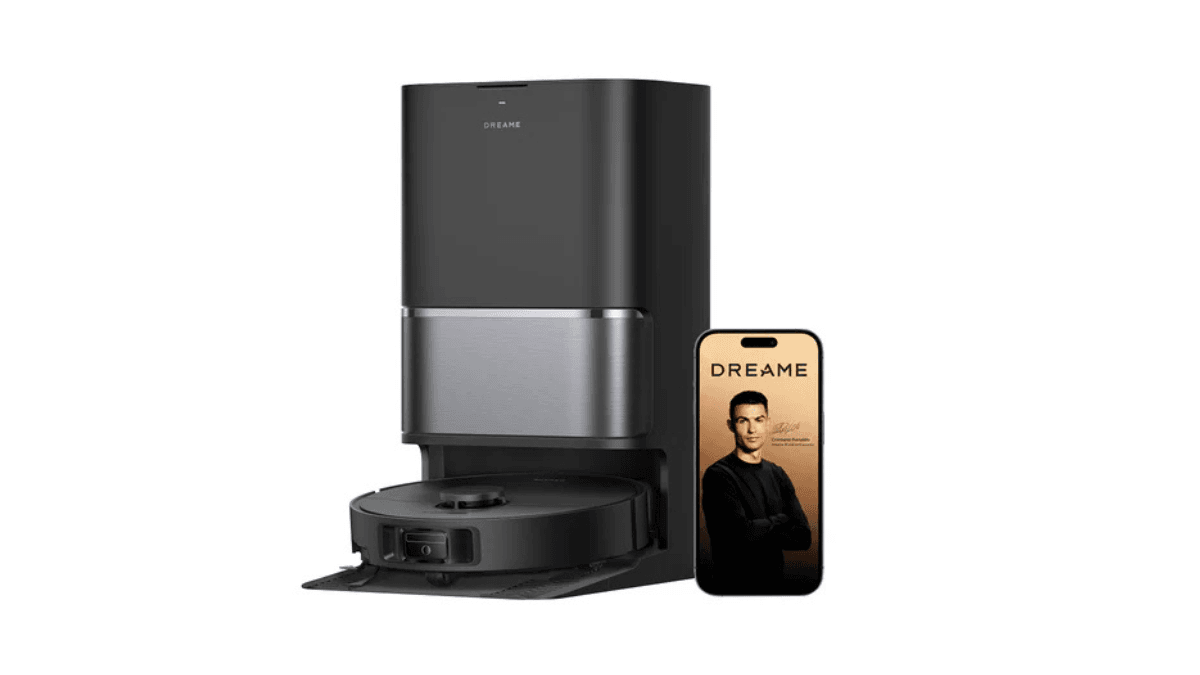 The automated cleaner that climbs over your thickest rugs 1 Black Dreame robot vacuum in a dark docking station beside a smartphone displaying Cristiano Ronaldo in India.