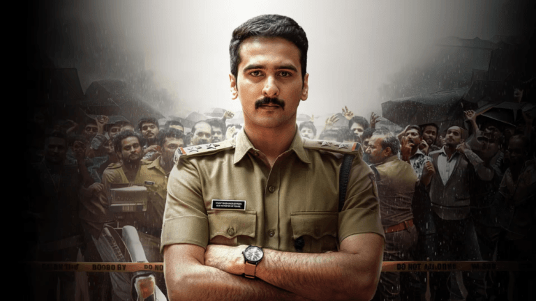 The Malayalam police mystery tailored for a weekend watch 2 Shane Nigam as a police officer with arms crossed, standing before a crowded village scene in Malayalam movie Dridam.