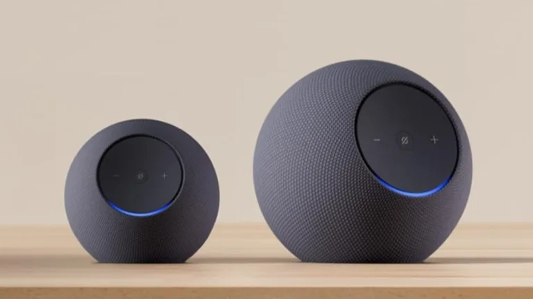 Two grey spherical Amazon Echo smart speakers side-by-side on a wooden table, showing glowing blue light rings in India.