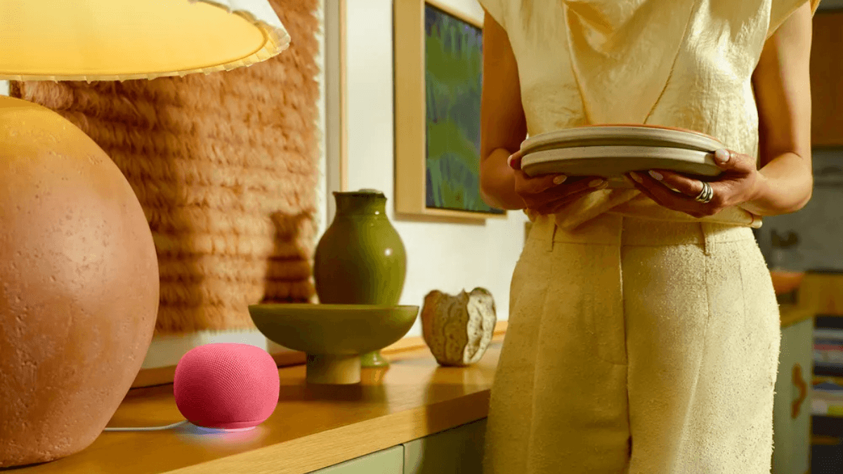 The smart speaker that remembers what you just said 1 Pink Google Home Speaker with a glowing light ring underglow on a wooden counter as a person holds ceramic plates.