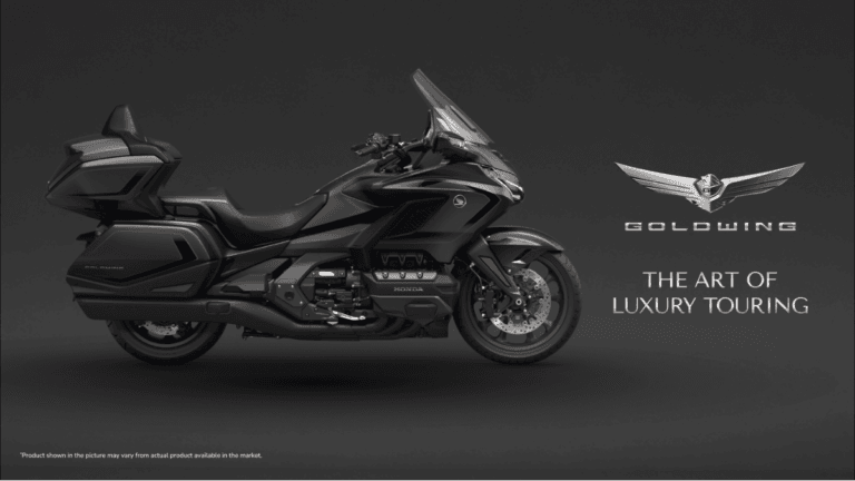 Does a motorcycle really need an airbag and an automatic box? 1 Side profile of a Gun Metal Black Honda Gold Wing cruiser on a dark background with promotional luxury touring text.