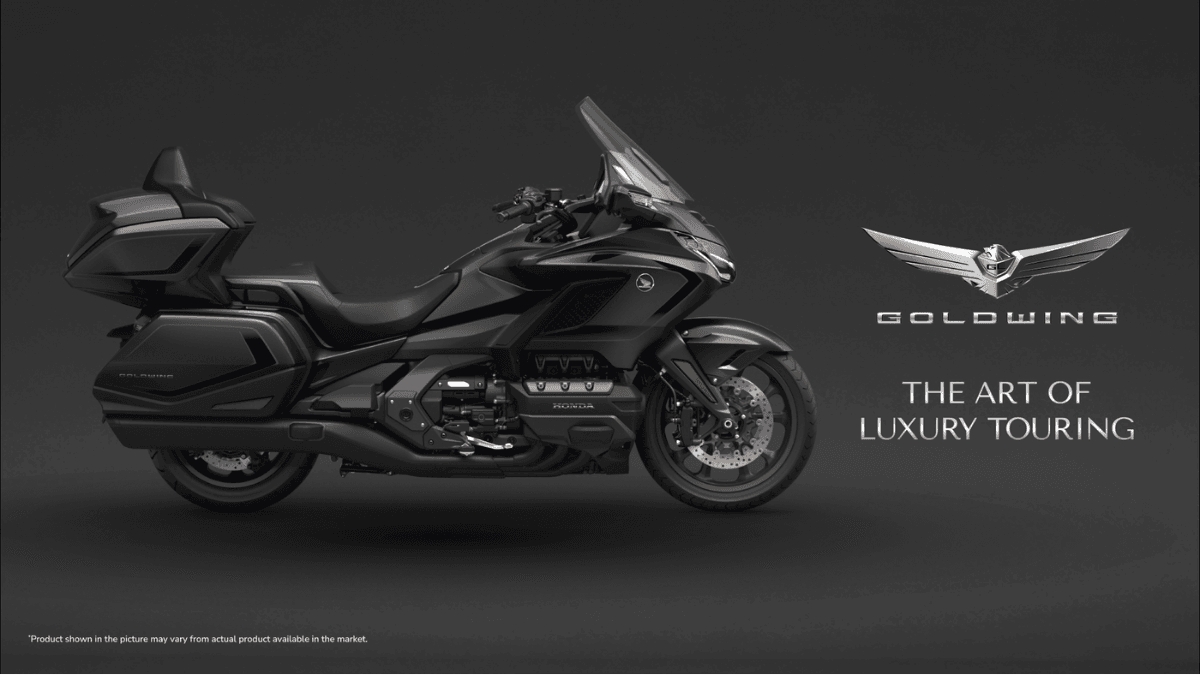 Does a motorcycle really need an airbag and an automatic box? 1 Side profile of a Gun Metal Black Honda Gold Wing cruiser on a dark background with promotional luxury touring text.