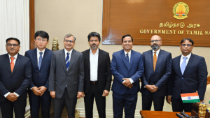 Seven men in business suits standing inside a Government of Tamil Nadu office during the Hyundai EV hub partnership.