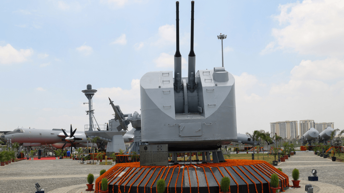 Is Lucknow's new naval open-air museum worth a weekend trip? 2 A large twin-barrel grey naval gun on a platform decorated with orange marigold flowers at the Lucknow museum.