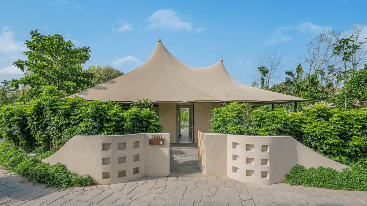 A luxury Rajasthan getaway built for family safaris 2 A premium canvas tented suite exterior with a stone pathway, low courtyard wall, and lush green hedges in Rajasthan.