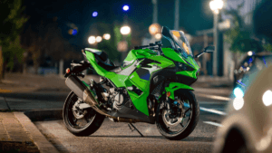 Lime green Kawasaki Ninja 500 motorcycle parked on its side stand on a city street at night during a metro commute.
