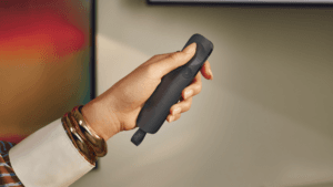 Hand holding a sleek dark grey Logitech Spotlight 2 presentation remote control highlighting its ergonomic force sensitive...