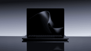 A black laptop open on a glossy surface displaying a smooth dark wave on screen, previewing premium Windows hardware.