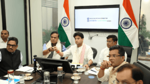 Indian officials pressing a button at a conference table with national flags, launching the Muga silk Mission Senehjori.