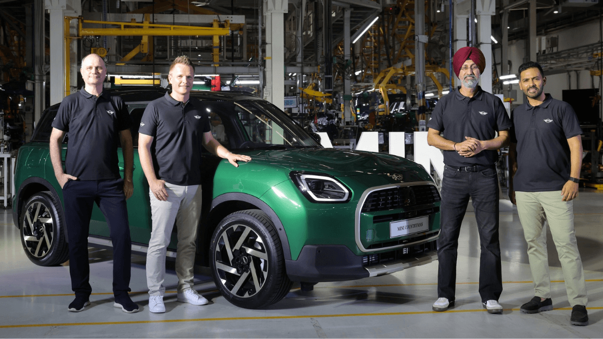Can a 66% buyback guarantee fix luxury car depreciation? 1 Four executives posing beside a green MINI Countryman SUV on the Chennai factory production line.