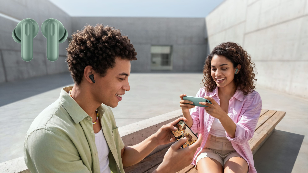 At ₹3,299 these earbuds block noise for up to 27 hours 2 A man and a woman sit on an outdoor bench playing mobile games while wearing black and green wireless earbuds.