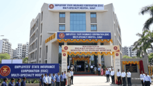 Surat ESIC multi-specialty hospital building facade with people standing under a decorated ceremonial archway in India.