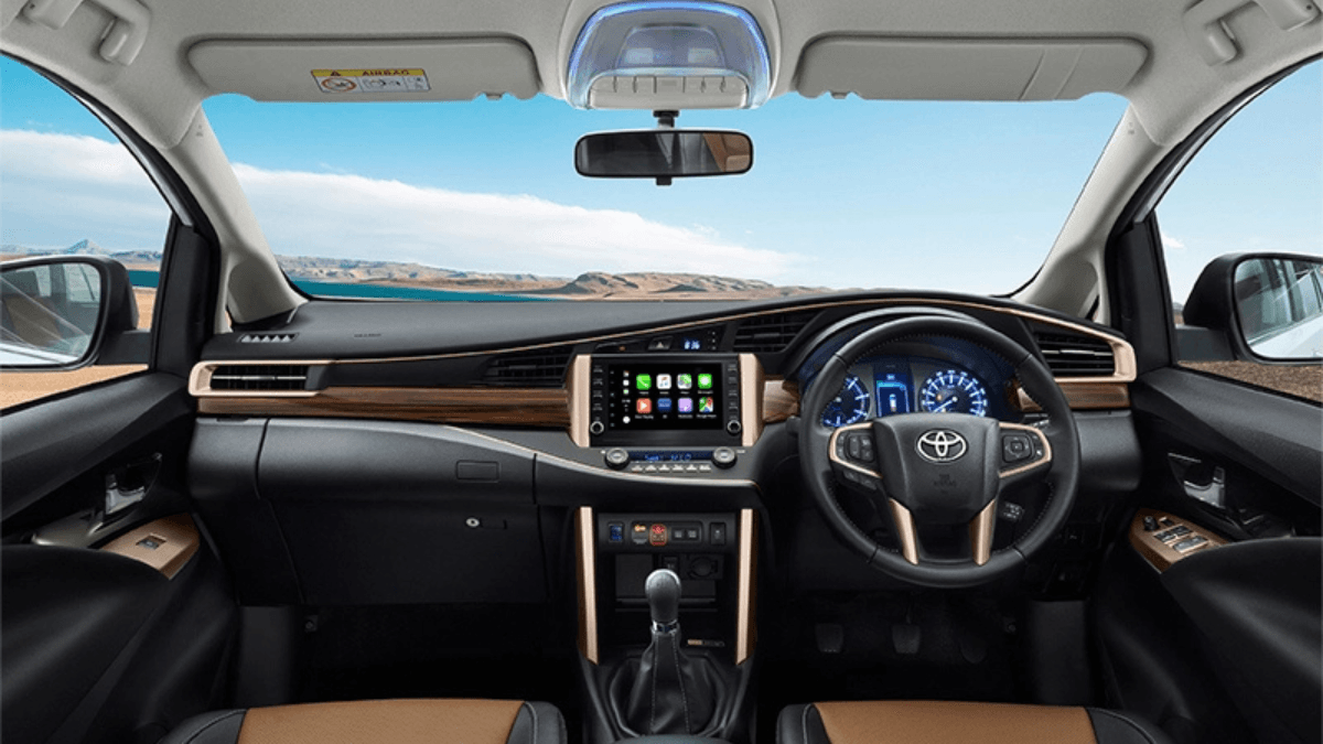 Car cabin dashboard with copper bezels, wood highlights, touchscreen, manual gear stick, and dual-tone seats in India.