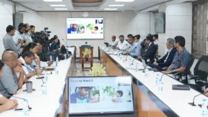 Officials in a press room looking at screens displaying a Varya AI video generation comparison slide in India.