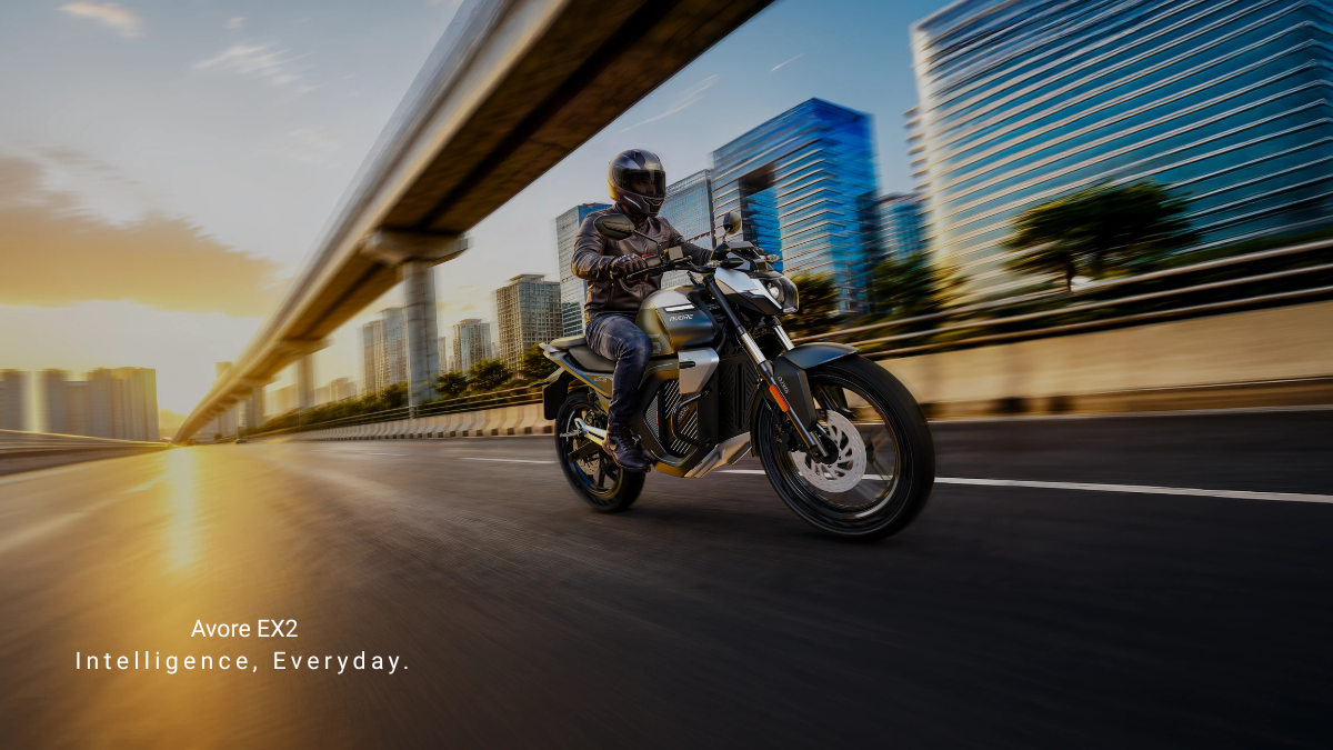 Can a standard wall socket power a 260km electric bike 1 Rider wearing leather jacket on grey Avore EX2 electric motorcycle commuting past city skyscrapers at sunset.