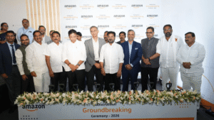 Officials stand behind a floral display in front of an Amazon groundbreaking backdrop at a ceremony in Hyderabad.