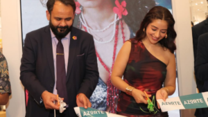 A man in a suit and a woman in a patterned dress cutting an AZORTE ribbon with scissors at a store event.