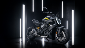 Black cruiser motorcycle with yellow fuel tank accents parked in a dark studio between vertical light tubes, cruiser.