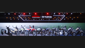 Ten Honda scooters and motorcycles displayed side-by-side on an illuminated stage in India.
