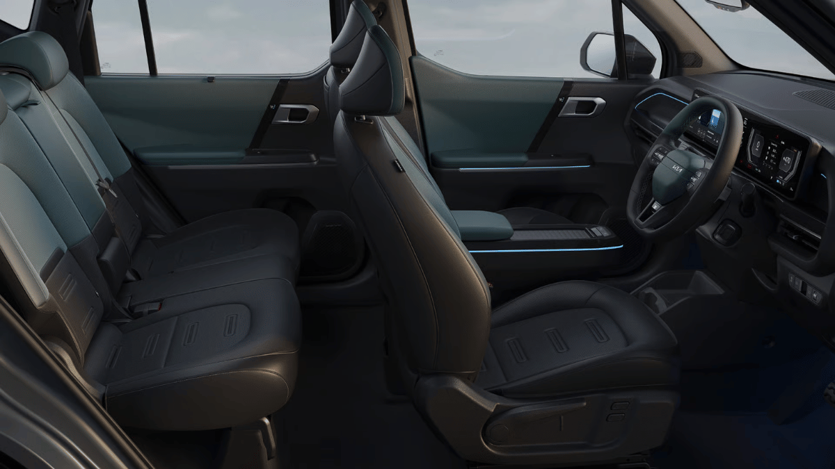 Cabin interior featuring dual-tone seats, steering wheel, dashboard displays, and ambient lighting for the Kia Syros.
