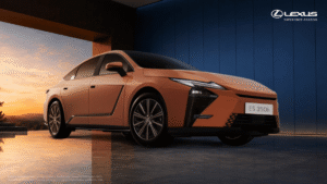 Copper-coloured Lexus ES 350h sedan displayed in a modern studio against a blue wall with a sunset background.