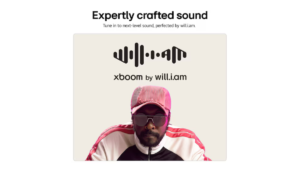 Musician will.i.am wearing a pink cap and sunglasses below a black xboom logo on a light background speaker.
