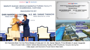 Narendra Modi and Sanae Takaichi stand on a stage next to an aerial graphic view of a factory plant in Haryana.