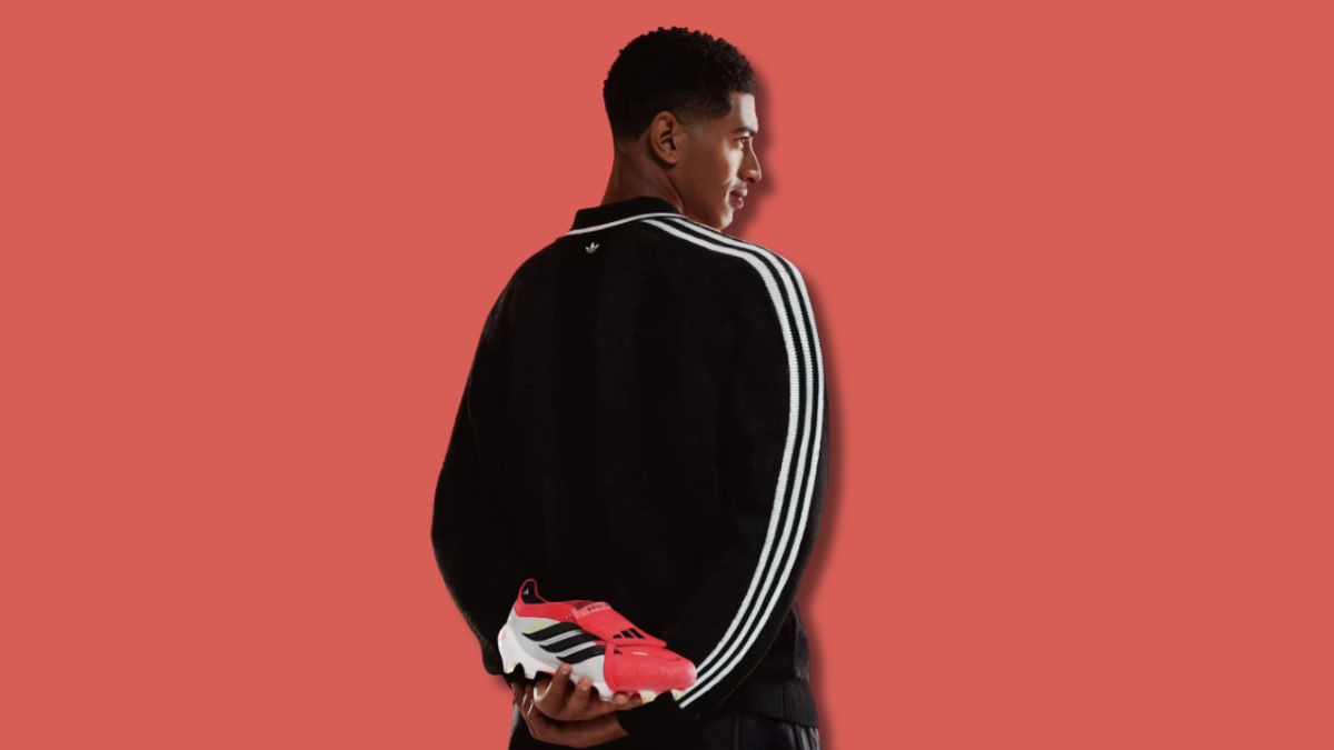 The footwear defining this season of global football 1 A man from behind holding a red and white football boot with a fold-over tongue, displaying footwear design.