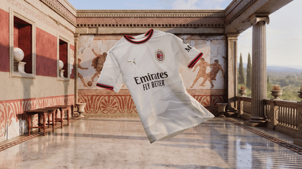 The shirt Inzaghi wore in spirit built for extreme heat 1 White short sleeve AC Milan away jersey with gold logo and red collar floating in a stone courtyard setup.