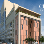 Multi-storey hotel building with balconies on left, pink exterior panels on right, and text overlay under a blue sky.
