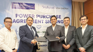 Five men stand left to right, the two in the centre holding black folders in front of a corporate signing banner.