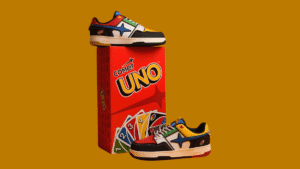 Multi-coloured sneaker atop a red card box with a second shoe on the right against a yellow background collection.