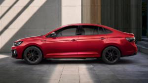 Red Volkswagen Virtus sedan in side profile with black alloy wheels against a modern grey wall with geometric shadows.